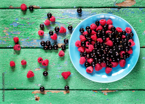 Принти на полотні Summer berries on blue plate on old rustic painted cracky green (turqouise) wooden background