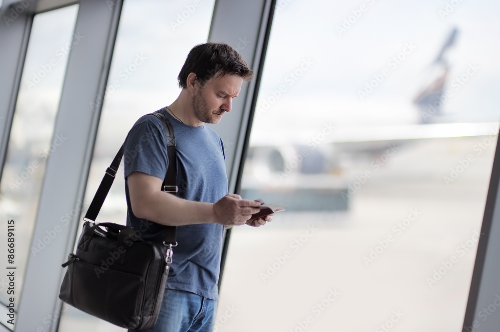 Male passenger at the airport with airplane on background