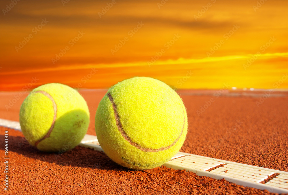 Tennis balls on a tennis clay court in the sunset