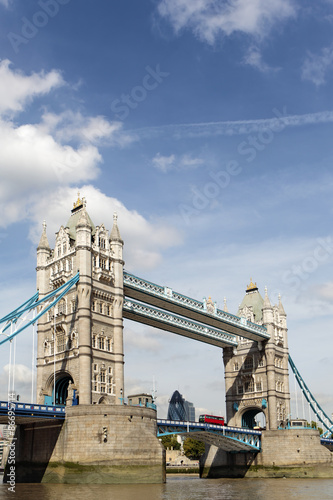 Tower Bridge London England side view with financial district buildings in the distance and red double decker bus photo vertical