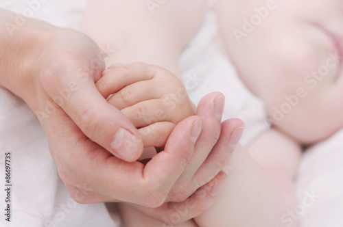 close up mother's hand holding little hand of her baby
