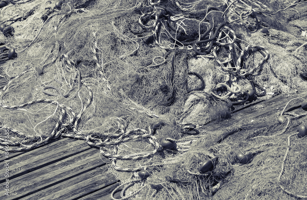 Fototapeta premium Fishing net laying on wooden pier, black and white