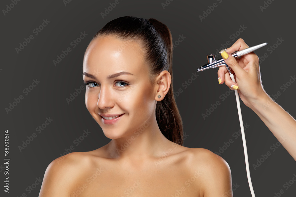 Fototapeta premium visagist making makeup for model with aerograph