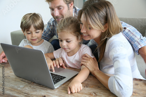 Parents with kids at home using laptop computer