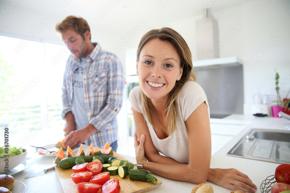 Portrait of cheerful woman in kitchen, boyfriend preparing lunch