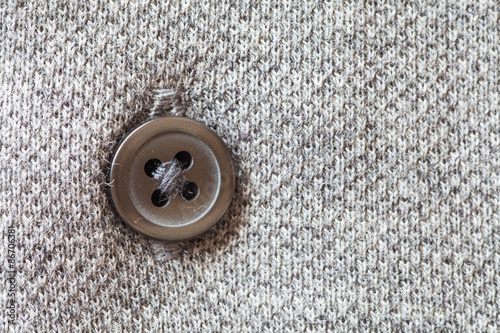 Close - up brown plastic button on grey shirt