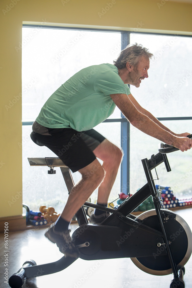 Fototapeta premium Senior man using a spinning bike