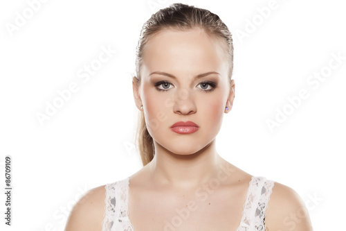 Serious young blonde with make up on a white background