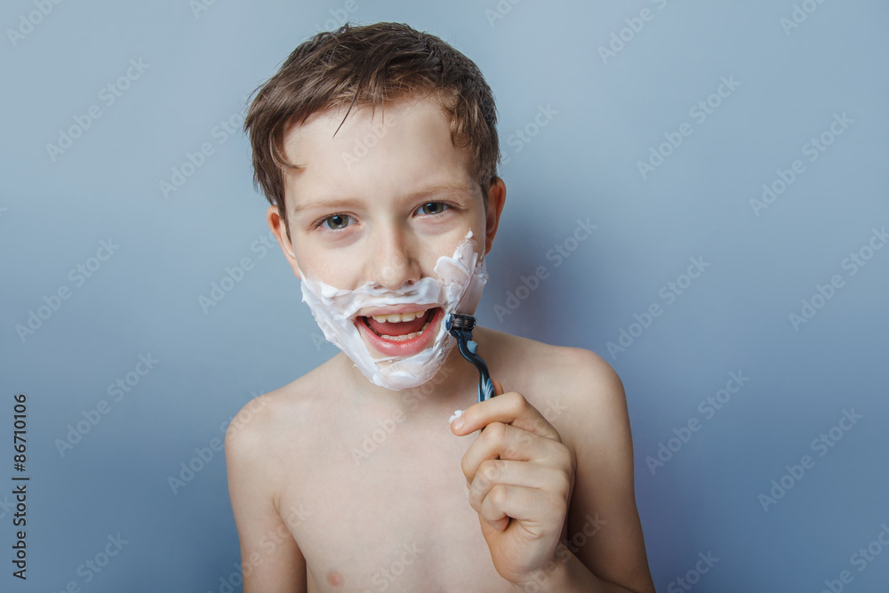Fototapeta premium Boy teenager European appearance decade shaves face on a gra