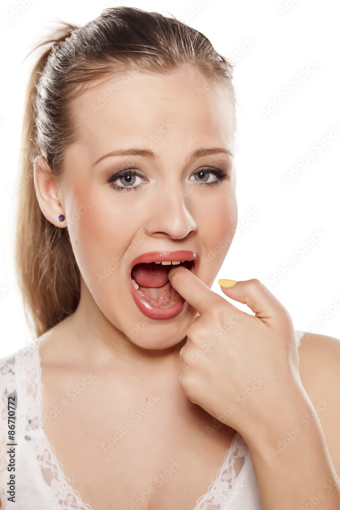 unhappy young girl showing pointing a finger at her aching tooth unhappy young girl showing pointing a finger at her aching tooth