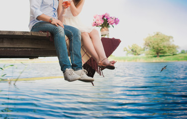 Pretty strong young loving couple sitting on the bridge over the river, next to a bouquet of peonies, lifestyle, concept, love, tenderness