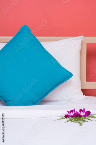 white and blue pillows with orange wall background in the bedroo photo