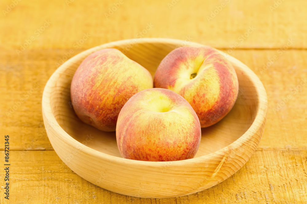 ripe fresh peaches on a plate on wooden background ripe fresh peaches on a plate on wooden background