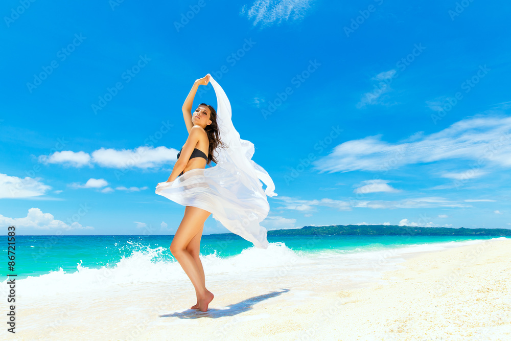 Young beautiful girl in bikini with white cloth on the beach of