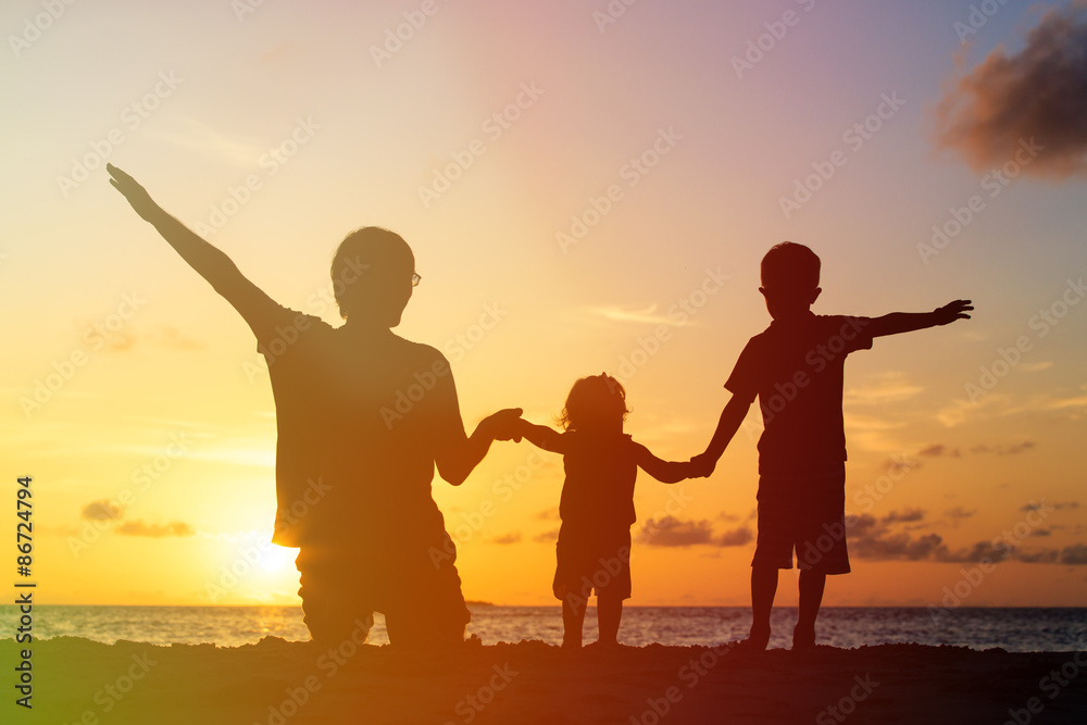 Fototapeta premium father with two kids at sunset beach