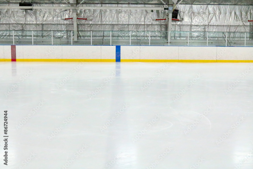 Naklejka premium View across the empty ice of an indoor hockey rink with metal bleachers