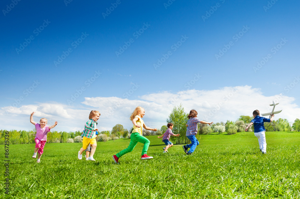 Boy with airplane toy and kids row running after Boy with airplane toy and kids row running after