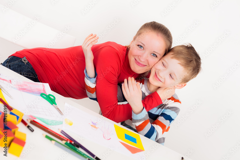 Happy son and mother hugging each other at desk Happy son and mother hugging each other at desk