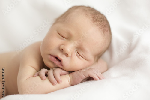 newborn baby sleeping in the arms on a light background