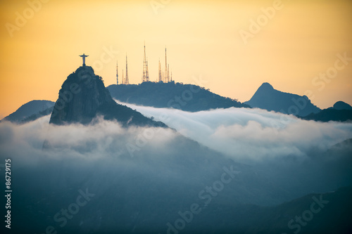 Corcovado mountain Christ the Redeemer standing in golden sunset above swirling mist clouds Rio de Janeiro Brazil