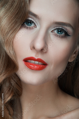 Portrait of beautiful young women with red lips, wavy hair, black eyeliner. Beauty. Studio shot. Black background.