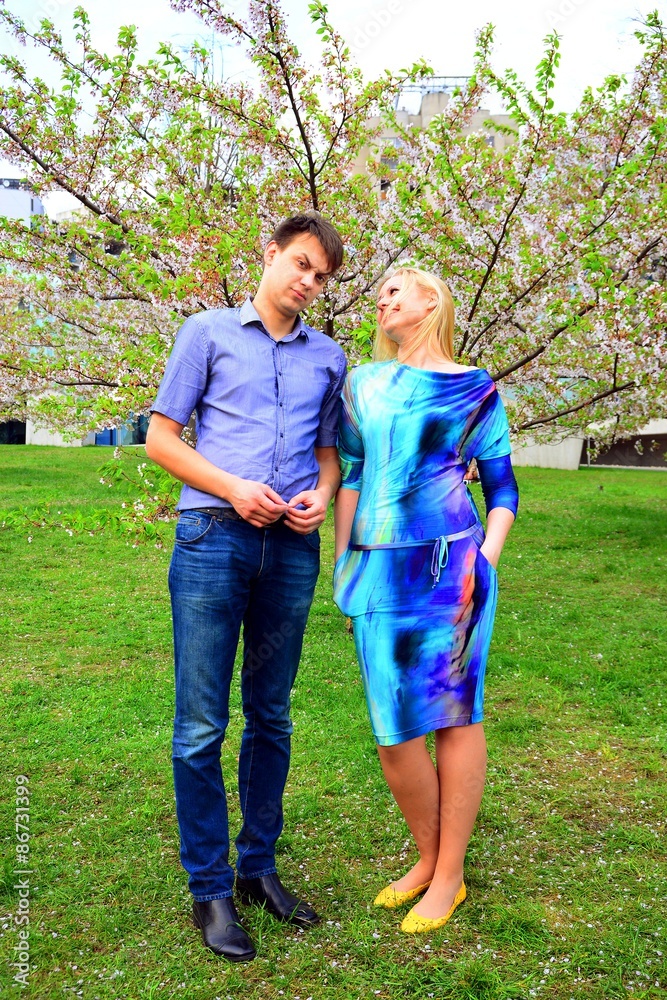 Fototapeta premium Young couple in the sakura's garden in park