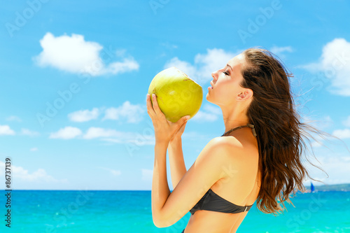 Young beautiful woman , drinking coconut water on tropical beach