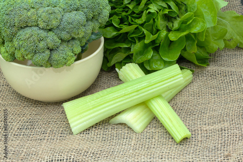 Green fresh vegetables. whole broccoli in a bowl with lettuce and celery on the tablecloth