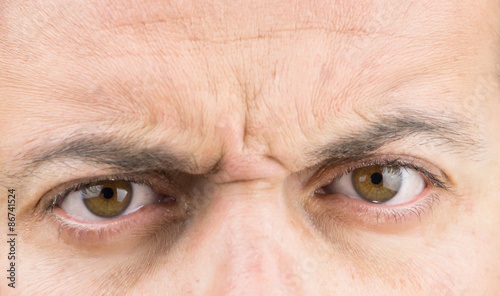 Upper part of males face closeup on angry eyes