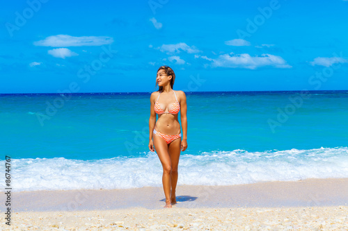 Beautiful young girl in bikini on a tropical beach. Blue sea in © frolova_elena