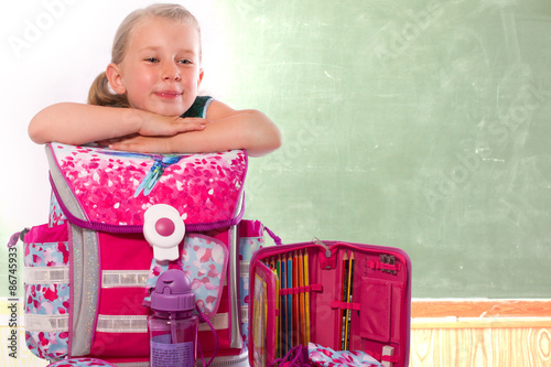 Foto stolzes Mädchen zeigt im Klassenzimmer ihre Schulsachen