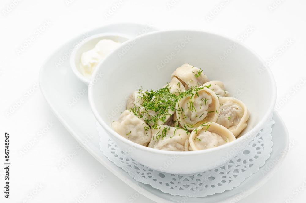 Russian traditional dish ravioli with sour cream isolated on white.