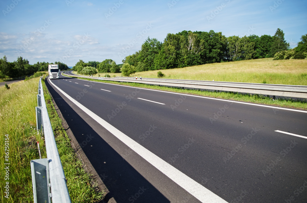 Empty asphalt expressway with white truck arriving from afar in the countryside