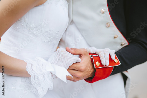 A groom in a hussar uniform holding his wifes hand