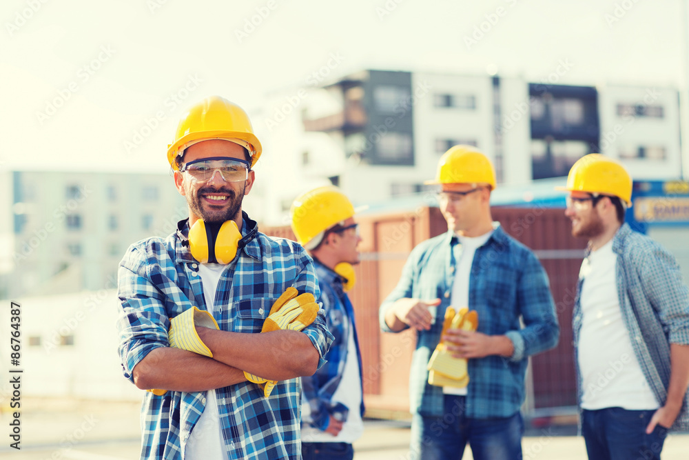 group of smiling builders in hardhats outdoors group of smiling builders in hardhats outdoors