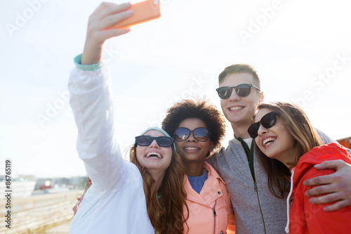 smiling friends taking selfie with smartphone