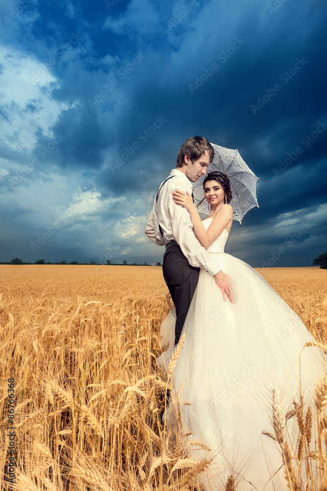 Bride and groom in wheat field with beautiful blue sky