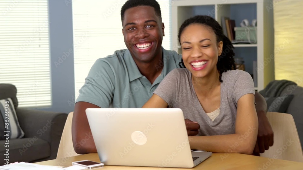 Happy young black couple with laptop and bills Happy young black couple with laptop and bills