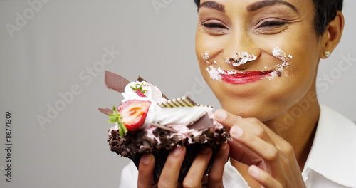 Foto Black woman making a mess eating a huge fancy dessert