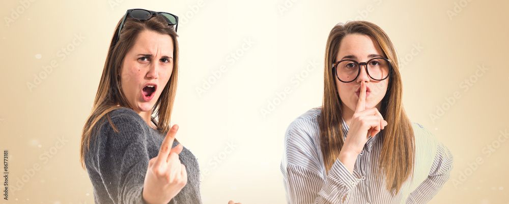 Twin sisters making silence and horn gesture Twin sisters making silence and horn gesture