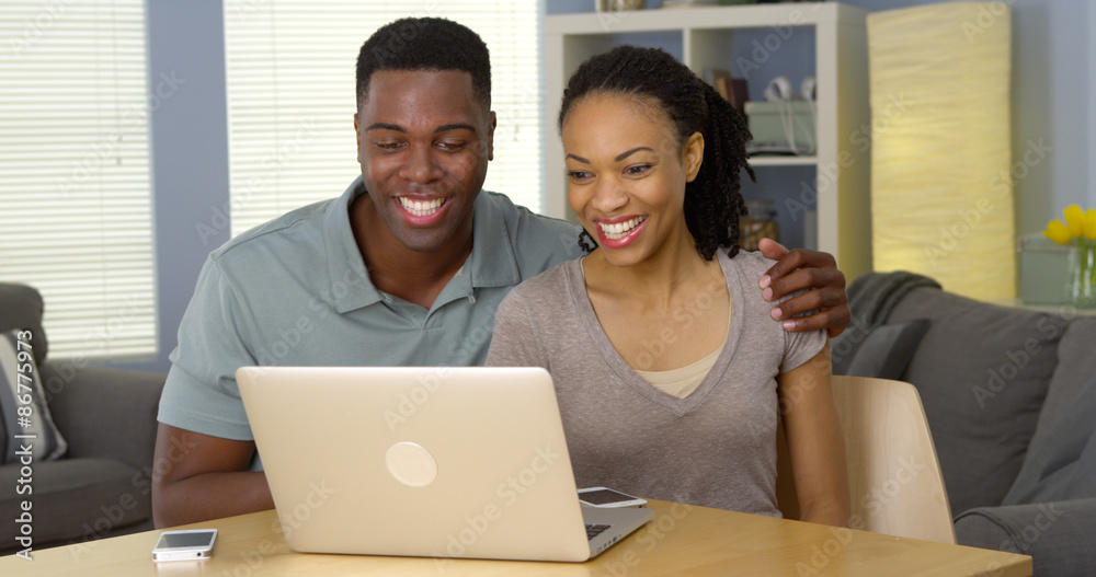 Young black couple watching funny video on laptop
