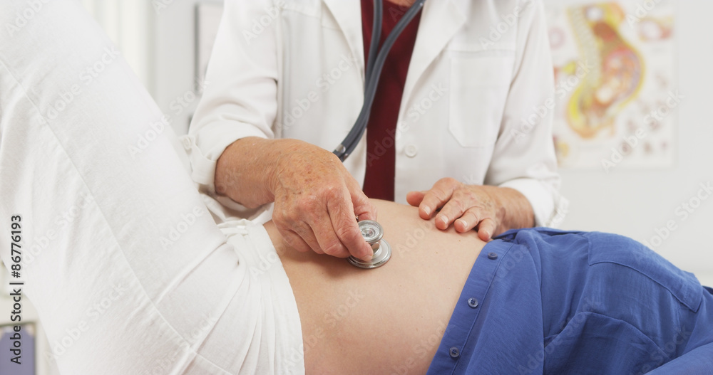 Senior doctor checking pregnant woman's belly