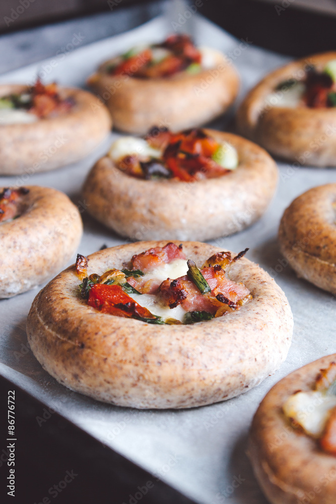 Mini pizzas on a baking paper in a pan