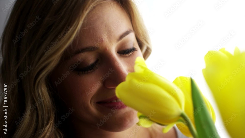Young blonde woman smelling yellow tulips Young blonde woman smelling yellow tulips