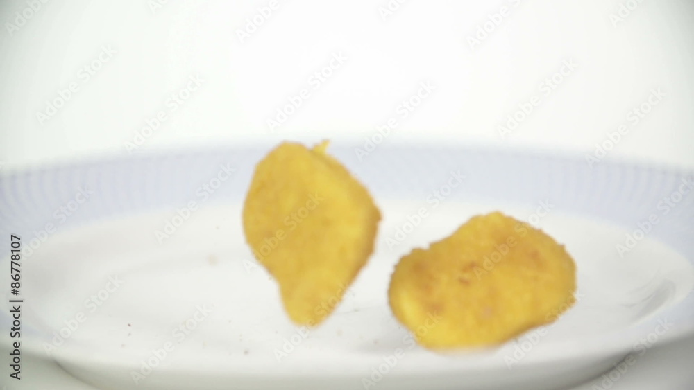 Roasted Chicken nuggets falling on white plate Roasted Chicken nuggets falling on white plate