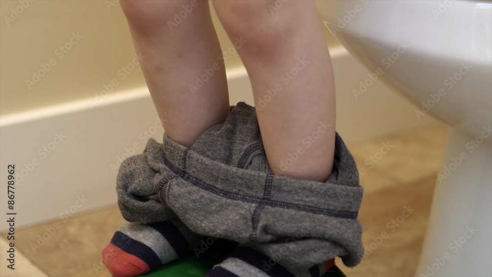 Little boy pulling up pants after going to the bathroom