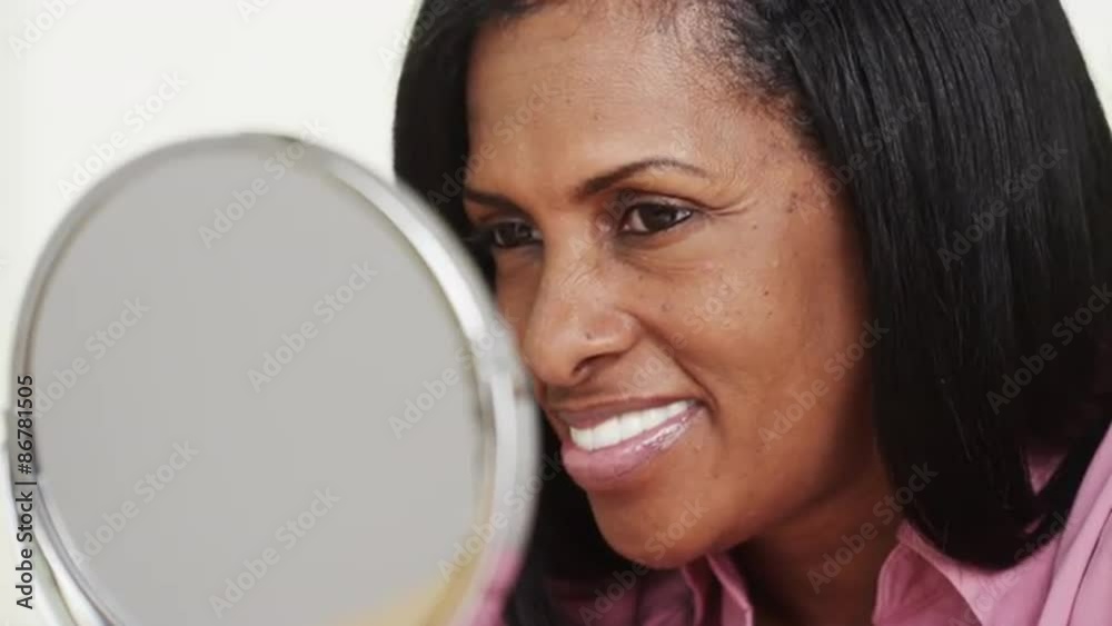 Elderly black woman looking at reflection in mirror Elderly black woman looking at reflection in mirror