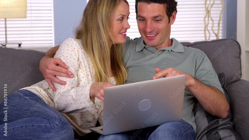 Cute couple using laptop on couch Cute couple using laptop on couch