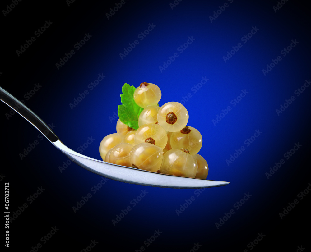 Fotografie white currants in spoon on a blue background
