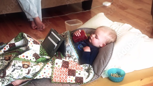 toddler sick with flu watching a tablet near mother photo